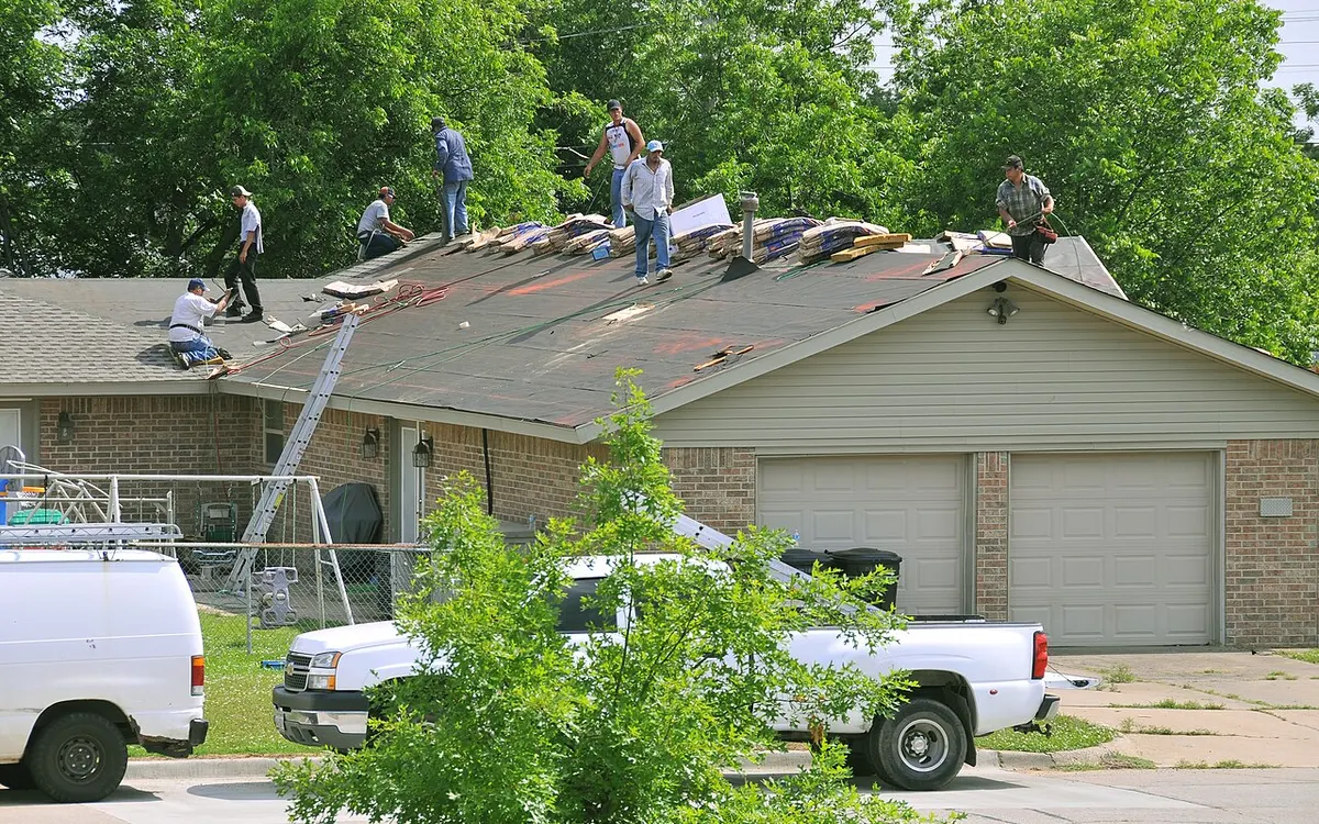 Roofing crew repairing shingles on a residential roof